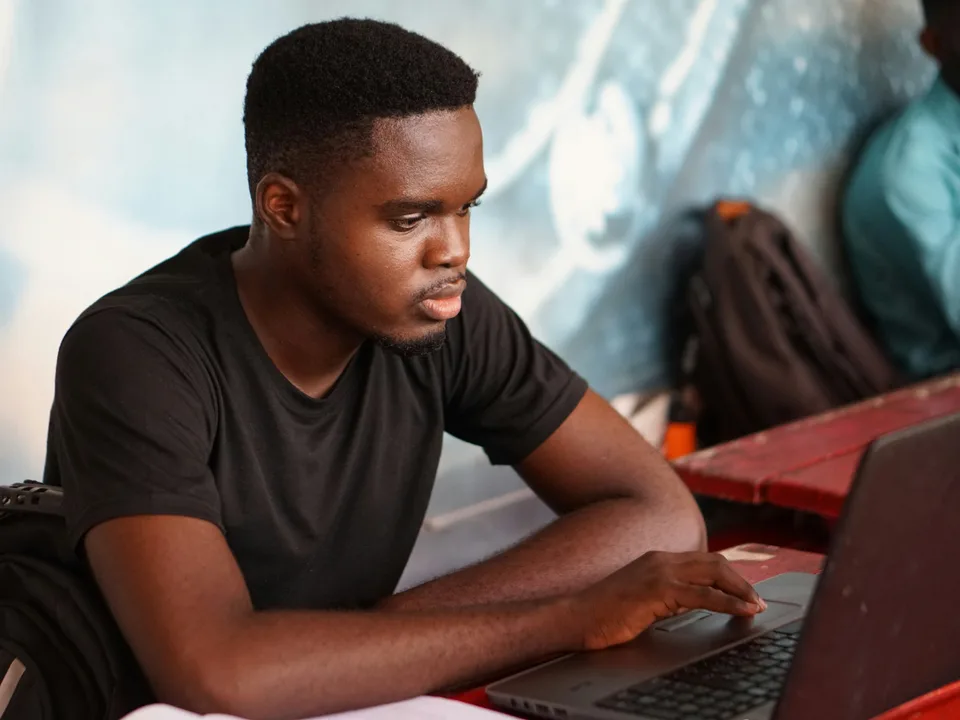 A person working at a laptop, one hand on the trackpad, concentrating on the screen.